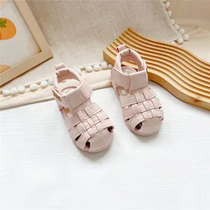 Detail view of pink closed-toe children's sandals with velcro strap on wooden surface