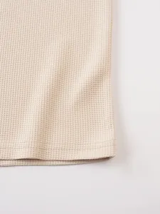 Detailed close-up of beige waffle knit fabric texture and hem stitching on men's T-shirt