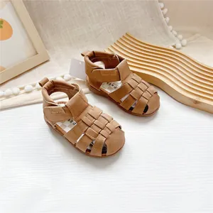 Detail view of brown closed-toe children's sandals with woven design and velcro strap.