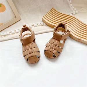 Close-up of stylish brown toddler leather sandals with woven closed-toe and velcro strap.