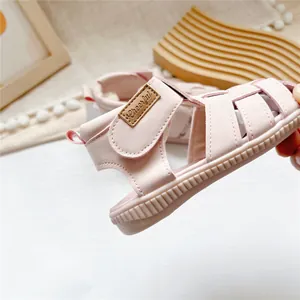 Close-up of pink leather children's sandal with Velcro strap and Cheerful label