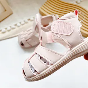 Macro view of pink baby sandals showing soft woven straps and secure Velcro strap detail.