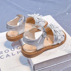 Shiny silver girls princess sandals featuring lace bow details and soft brown rubber sole