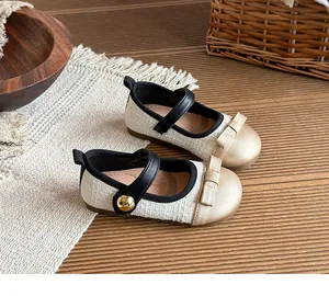 Close-up detail of tweed children's Mary Janes with gold bow and black strap details.