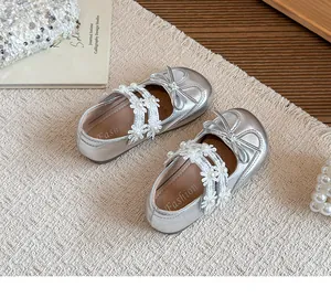 Close-up of silver girl's princess shoes with floral lace straps and bow detail