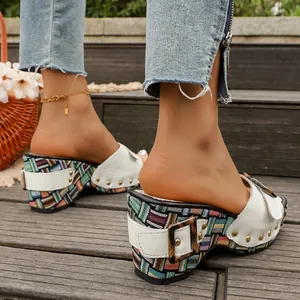 Detailopname van damesplatformsandalen met geweven hak en gouden details van studs