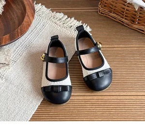 Close-up detail of girls' black and cream tweed Mary Jane shoes with a leather bow