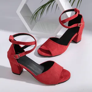 Macro view of red faux suede chunky heel sandals with crisscross ankle straps