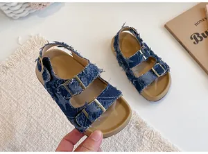 Dettaglio di sandali in denim sfrangiato per bambina con motivo a stelle e fibbie dorate.
