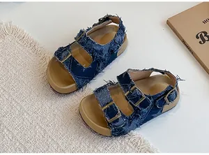 Dettaglio di sandali piatti da bambina in denim con cinturini a doppia fibbia regolabile