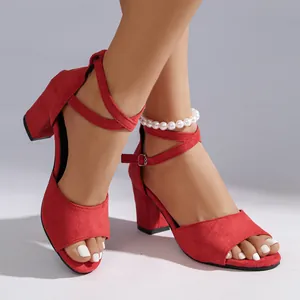 Close-up of red suede chunky heel sandals with cross straps and pearl anklet detail