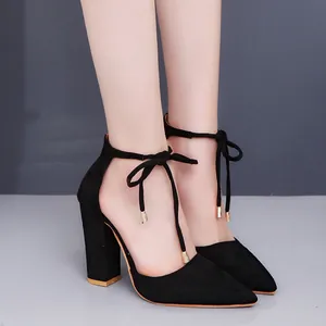 Primer plano de salones de ante negro con punta fina, tacones anchos y lazos al tobillo.