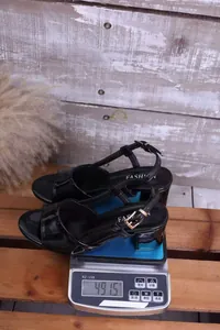 Paio di sandali neri in vernice con tacco alto pesati su una bilancia digitale a 491,5g