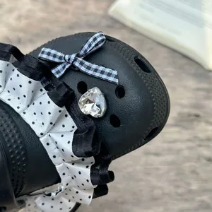 Detailed view of girl's black clog with polka dot ruffles and heart gemstone