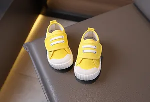 Dettaglio di scarpe in tela gialla per bambini con resistenti cinturini a strappo.