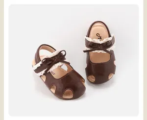 Detailweergave van bruine babysandalen voor meisjes met kant en strik