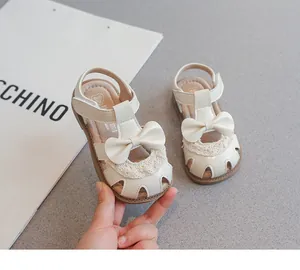 Primer plano de sandalias beige para niña con lazo y elegantes detalles de encaje