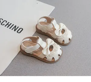 Primer plano de sandalias para niña en color crema con un lazo y encaje elegante