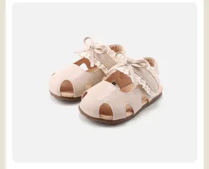 Gedetailleerd zicht op de elegante kanten rand en strik op deze crème babysandalen voor meisjes