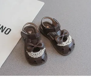 Primer plano de sandalias marrones para niñas con elegante lazo y encaje blanco