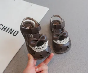 Vista de detalle de sandalias marrones para niñas con lazo lindo y adornos de encaje