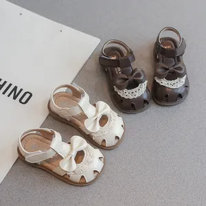 Sandalias cerradas para niñas con lazo y encaje en colores marrón y crema.