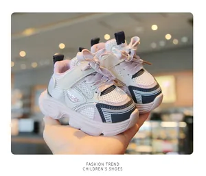 Macro view of pink and white breathable mesh baby sneakers held in hand for detail