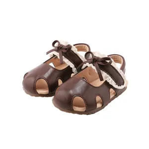 Bruine baby prinses sandalen met kant en strik detail, getoond in een studio view.