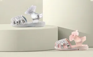 Detailed view of silver and pink sequined princess sandals for babies with mesh bows.