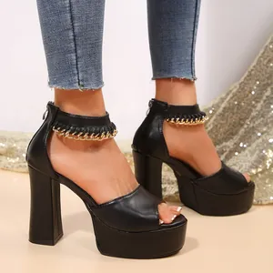 Detalle de sandalias negras con plataforma, tacón grueso y adornos de cadena dorada