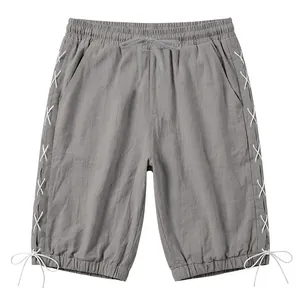 Detail view of grey linen three-quarter pants featuring side lace-up design and drawstring waist.