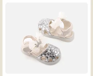 Close-up of sparkly silver sequins and white mesh bow with crown on baby girl sandals