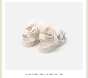 Close-up of girls' champagne princess sandals with elegant lace bow and sequin details