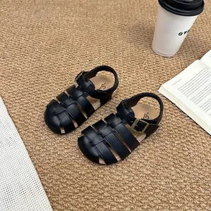 Close-up detail of retro black woven fisherman sandals for kids on a textured rug