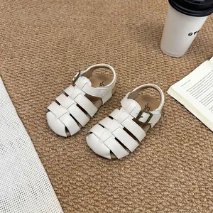 Detailed view of white children's woven Roman sandals on a cozy textured carpet.