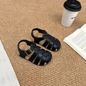 Detail view of retro black closed-toe Roman sandals for kids on carpet