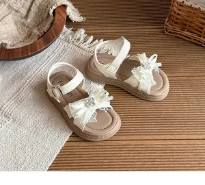 Sandales crème pour filles avec nœud en strass et dentelle sur fond de bois naturel