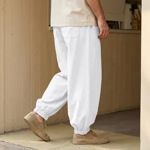 Detailed side view of loose white linen harem pants featuring elasticated ankle cuffs for men