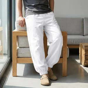 Detailed view of white linen joggers for men featuring elastic cuffs and drawstrings.