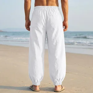 Rear view of white linen beach joggers for men in a scenic coastal setting