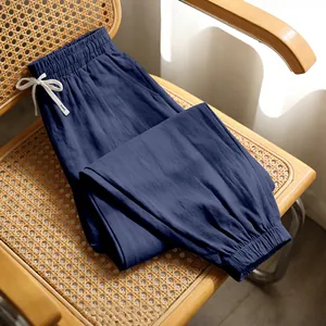 Detail view of navy blue linen men's leisure joggers resting on a rustic rattan chair.