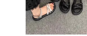 Gros plan sur des sandales argentées pour filles et des sandales noires sur tapis