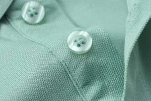 Macro view of light green polo shirt featuring breathable pique texture and matching buttons