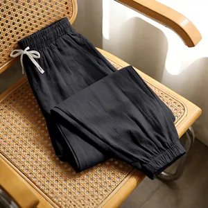 Detail of folded black men's linen casual joggers on a woven chair showing fabric texture