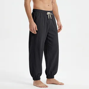 Detail view of men's loose black linen joggers with elastic cuffs and natural drawstring.