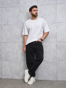 Detail view of men's black straight-leg denim jeans styled with white leather sneakers