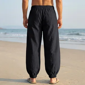 Back view detail of breathable black linen jogger pants for men on a summer beach