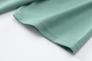 Detailed close-up of a double-stitched hem on a mint green breathable polo shirt.