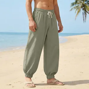 Men's breathable sage green linen jogger pants styled for a relaxed summer beach look.