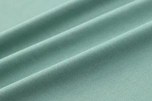 Macro view of mint green polo shirt fabric showing breathable bird-eye mesh texture
